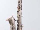 an old silver saxophone sitting on top of a wooden table