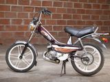 a small motor bike parked in front of a brick wall