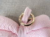 a pink bow tie with a gold ring on top of it