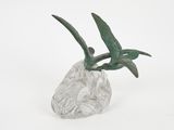 sculpture représentant un oiseau perché sur un rocher, sur fond blanc