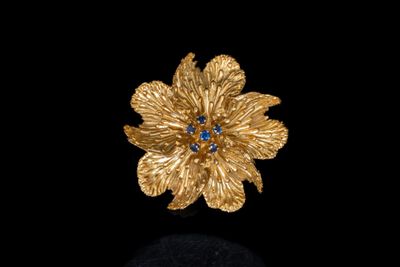une photo d'une broche en forme de fleur en or sertie de pierres bleues