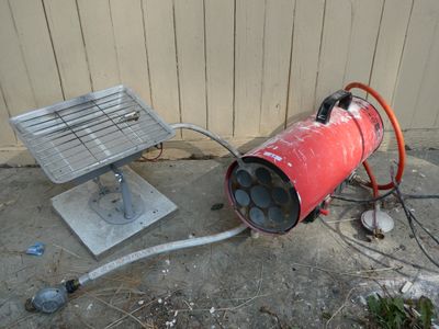 a red fire extinguisher sitting on the ground next to a metal grill