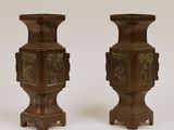deux vases marron ornés de motifs sur un fond blanc
