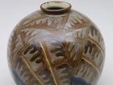 a brown and blue vase sitting on a white surface