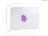 a purple stone in a clear box on a white surface