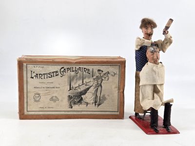 two figurines of a man cutting a man ' s hair in front of a box