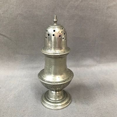 une vieille poivrière en argent percée de trous sur le dessus