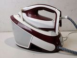 a red and white steam iron sitting on a table