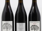 trois bouteilles de vin posées les unes à côté des autres sur une surface blanche