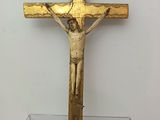 a gold cross on a glass table with a white wall in the background