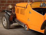 an orange car that is parked in front of a brick wall