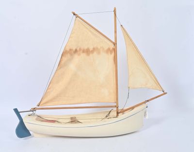 un petit bateau muni d'une voile sur une surface blanche
