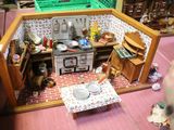 une cuisine miniature dans une maison de poupées, avec une table et des chaises