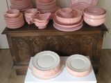 many pink plates and bowls on a wooden table