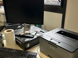 un ordinateur et une imprimante posés sur un bureau devant une fenêtre