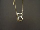 un collier en or sur lequel figure la lettre « b »