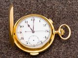 une montre de poche en or posée sur un tissu marron