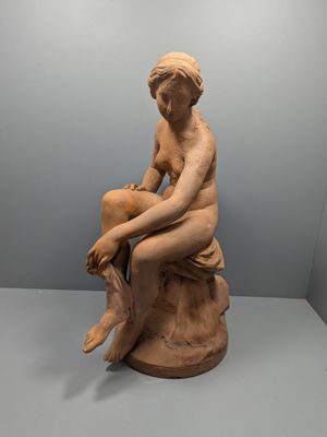 l'image d'une statue de femme assise sur un rocher