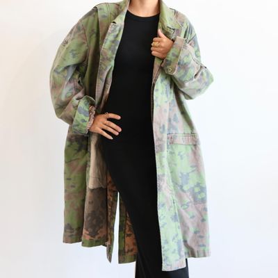 woman in a black dress and green jacket posing for a picture