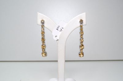 une paire de boucles d'oreilles dorées posées sur un présentoir blanc, sur une table