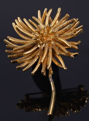 un gros plan d'une broche en forme de fleur dorée posée sur une surface noire