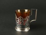 une tasse en argent et en verre munie d'une anse, posée sur une surface noire