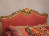 a bed with a red and gold headboard and pillows on it
