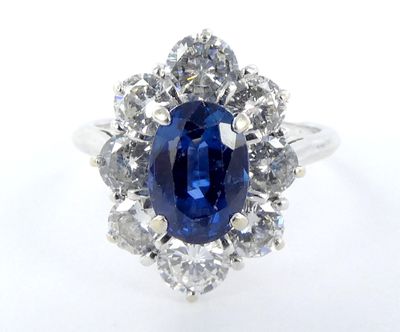 a close up of a ring with a blue sapphire surrounded by diamonds