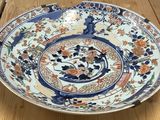 une grande assiette bleue et blanche posée sur une table en bois