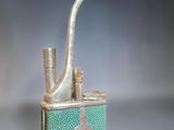 a green and gold cigarette case with a pipe sticking out of it
