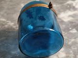a blue glass jar with a gold lid on a table