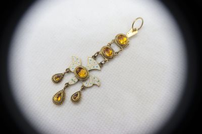a close up of a yellow and white butterfly charm on a white surface