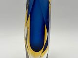 a blue and yellow vase sitting on a white surface