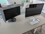 deux écrans d'ordinateur posés sur un bureau blanc