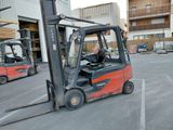 two forklifts parked in a parking lot in front of a building