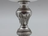 an antique silver goblet on a stand on a gray background