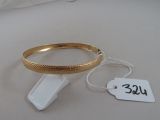un bracelet en or et une étiquette posés sur une table blanche