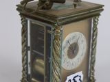 a small clock with a man sitting on top of it