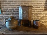 trois vases posés sur une table, avec un mur de briques en arrière-plan