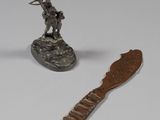 une statue en argent représentant un homme assis sur un rocher, à côté d'un couteau