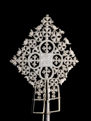 une image représentant une croix en argent posée sur un socle, sur fond noir