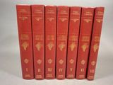 six livres rouges sont alignés sur une surface blanche