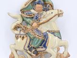 une figurine représentant un homme à cheval sur fond blanc