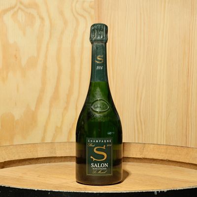 a bottle of wine sitting on top of a wooden barrel