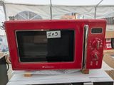 un micro-ondes rouge posé sur une table blanche