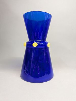 un vase en verre bleu orné d'un bouton jaune
