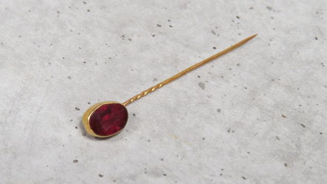 Épingle à cravate en or 750‰, sertie d’une pierre rouge. En règle...