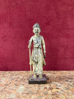 an old statue of a woman with a cane stands on a table