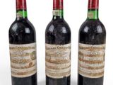trois bouteilles de vin rouge sont posées les unes à côté des autres sur une surface blanche
