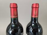 two bottles of wine sitting on top of a table next to each other